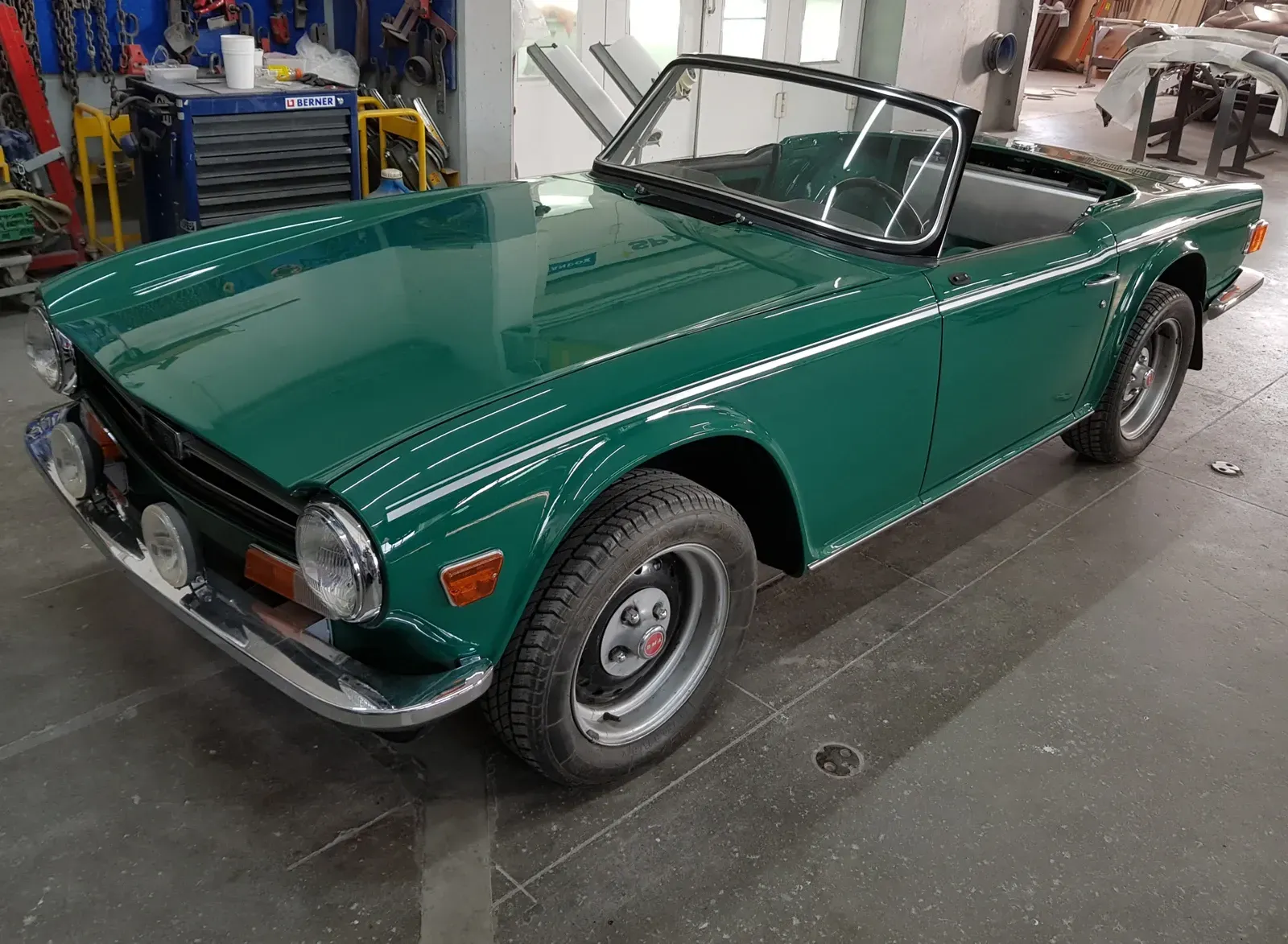 Une Triumph TR6 décapotable verte dans un garage.