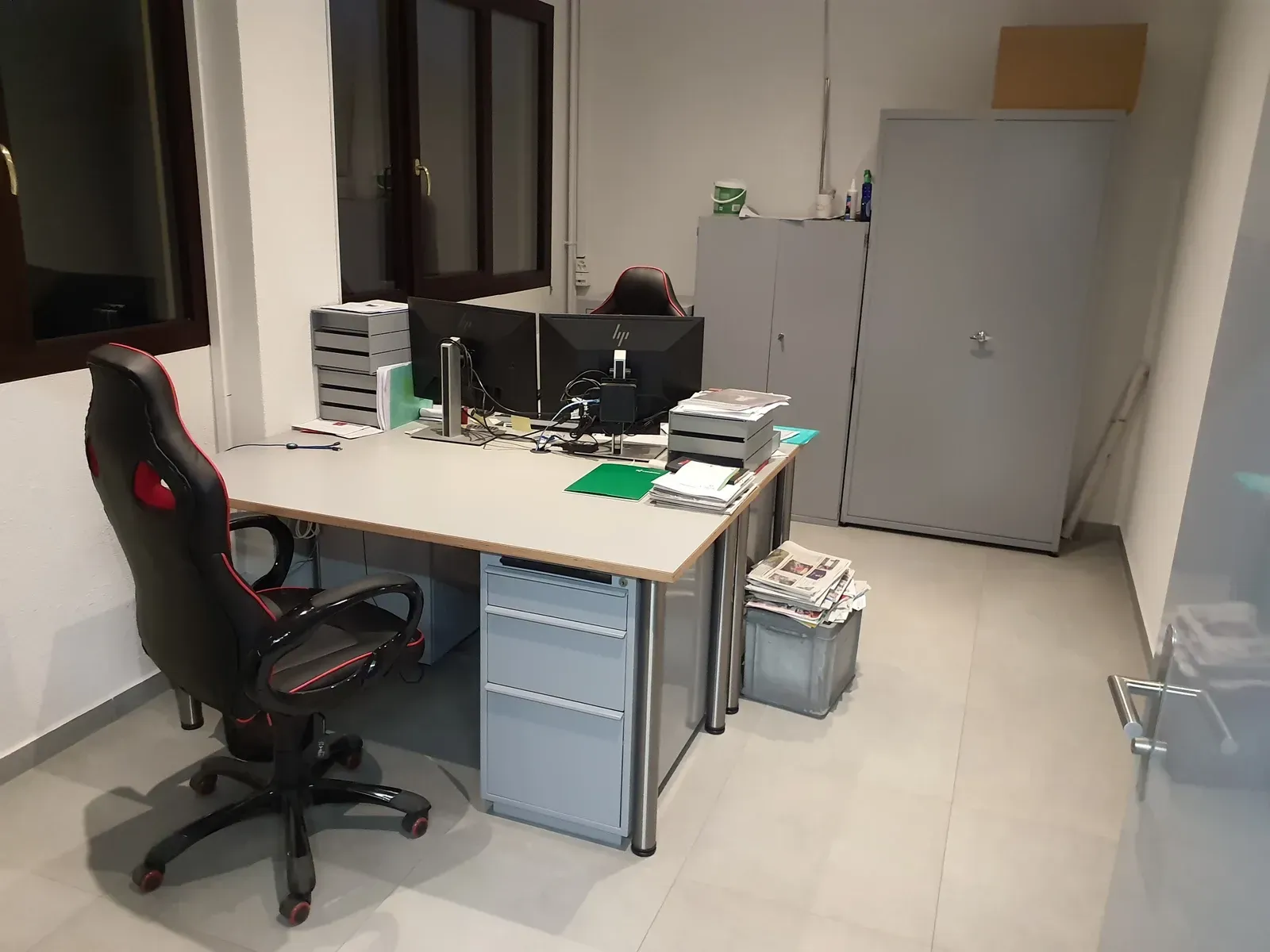 Bureau avec bureau, écrans d'ordinateur, chaise et armoires de rangement.