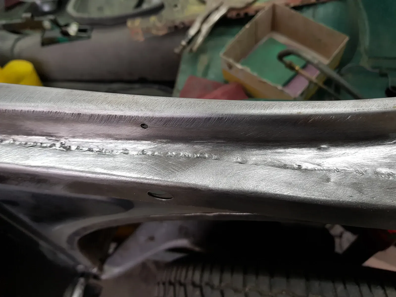 cadre de portière métallique de voiture avec des soudures visibles, montrant des travaux de réparation dans un atelier.