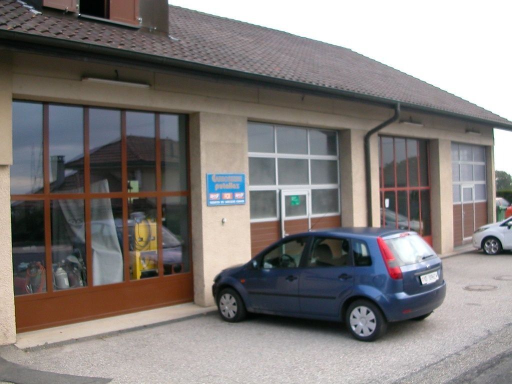 Une voiture bleue est garée devant le garage