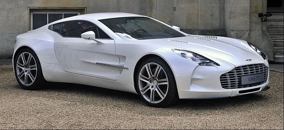 Aston Martin One-77 blanche garée sur du gravier.