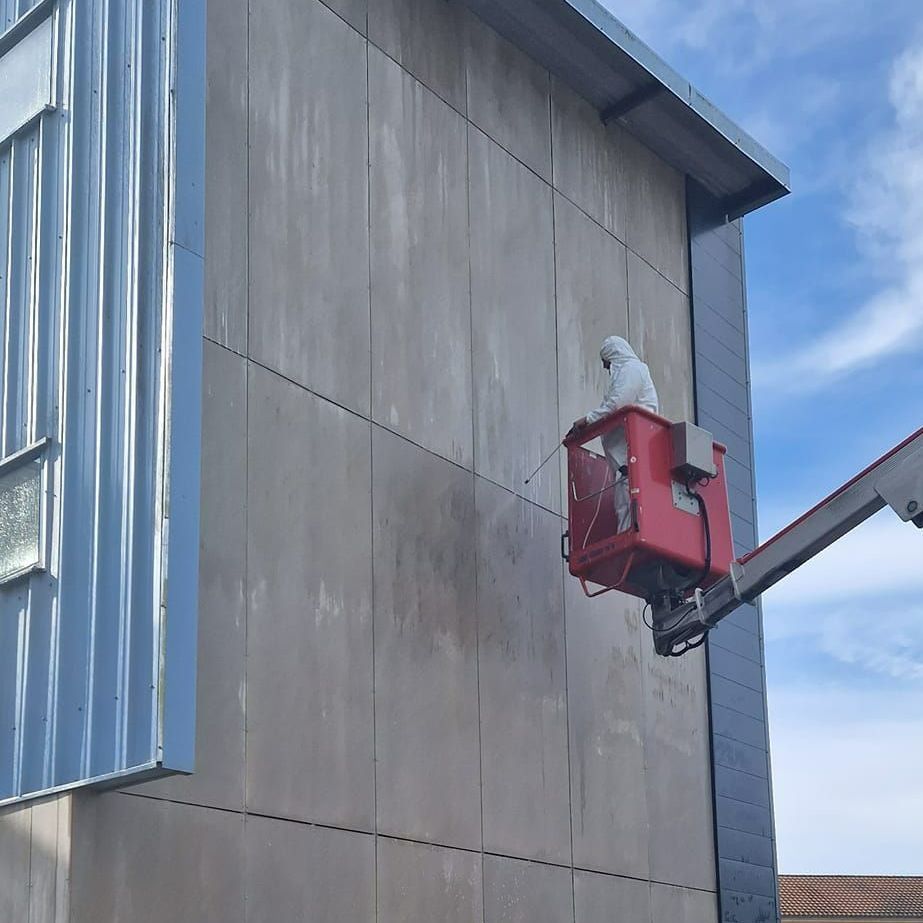 Professionnel sur une nacelle nettoyant une façade
