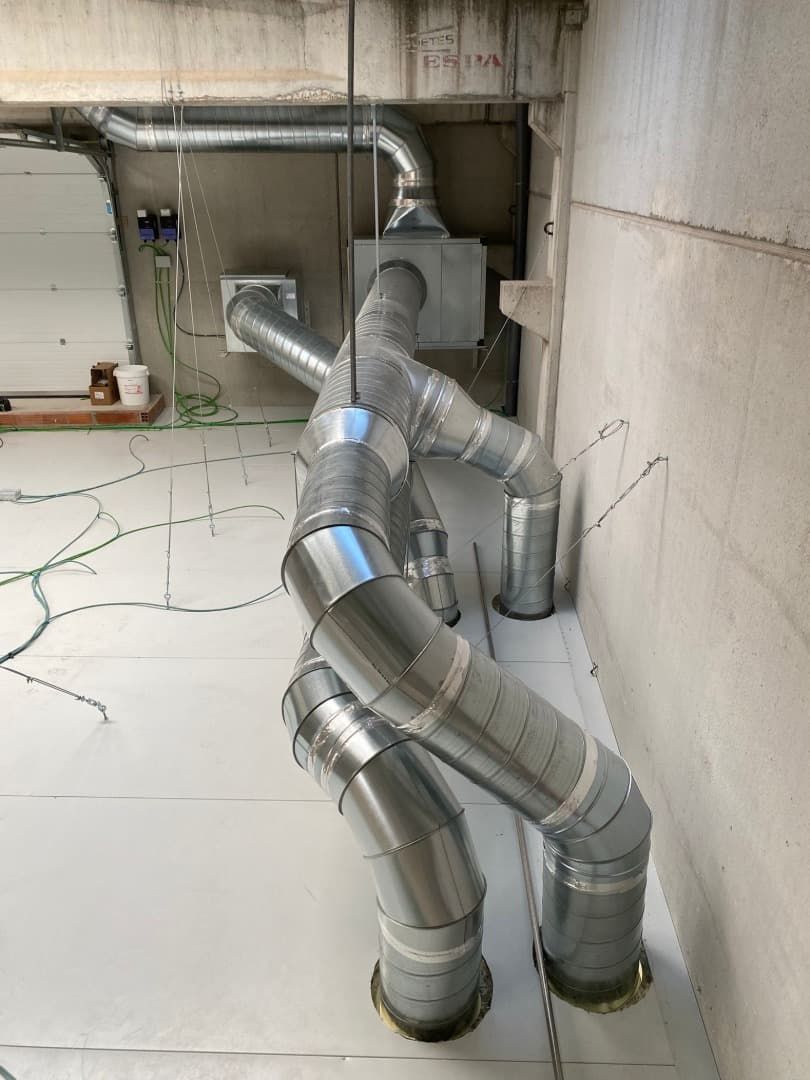 Conductos metálicos con curvas y conexiones en un entorno de construcción.