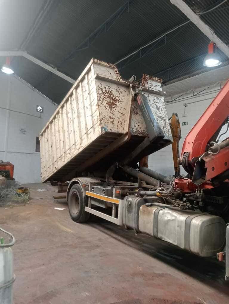 Un camión volquete está siendo levantado por una grúa en un almacén.