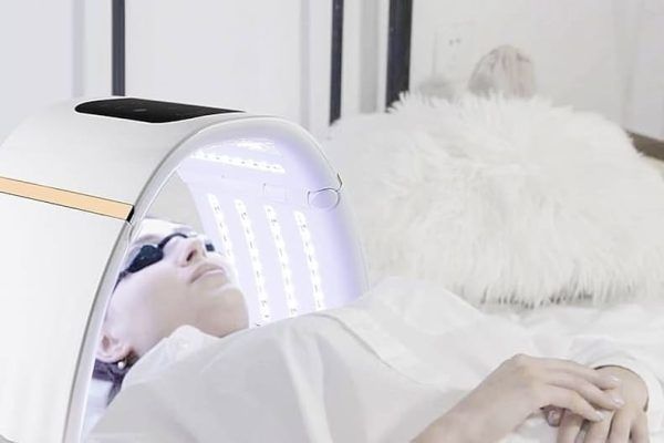 Una mujer está acostada en una cama con una luz en su cara.