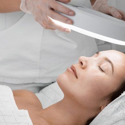 Una mujer está recibiendo un tratamiento facial con una lupa.