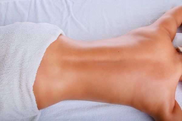 Una mujer está acostada en una cama recibiendo un masaje.