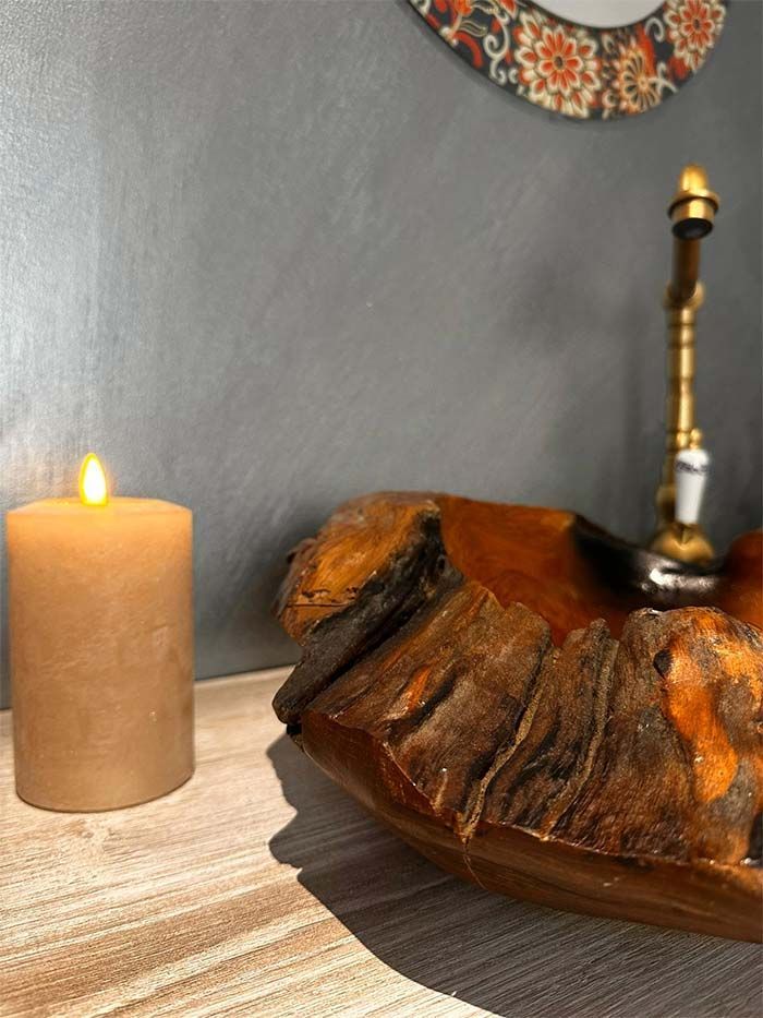 Se enciende una vela junto a un cuenco de madera sobre una mesa.