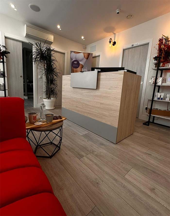 Una sala de espera con un sofá rojo y un mostrador de recepción.