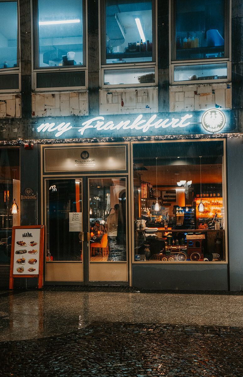 Die Vorderseite eines Restaurants namens „My Frankfurt“ ist nachts beleuchtet.