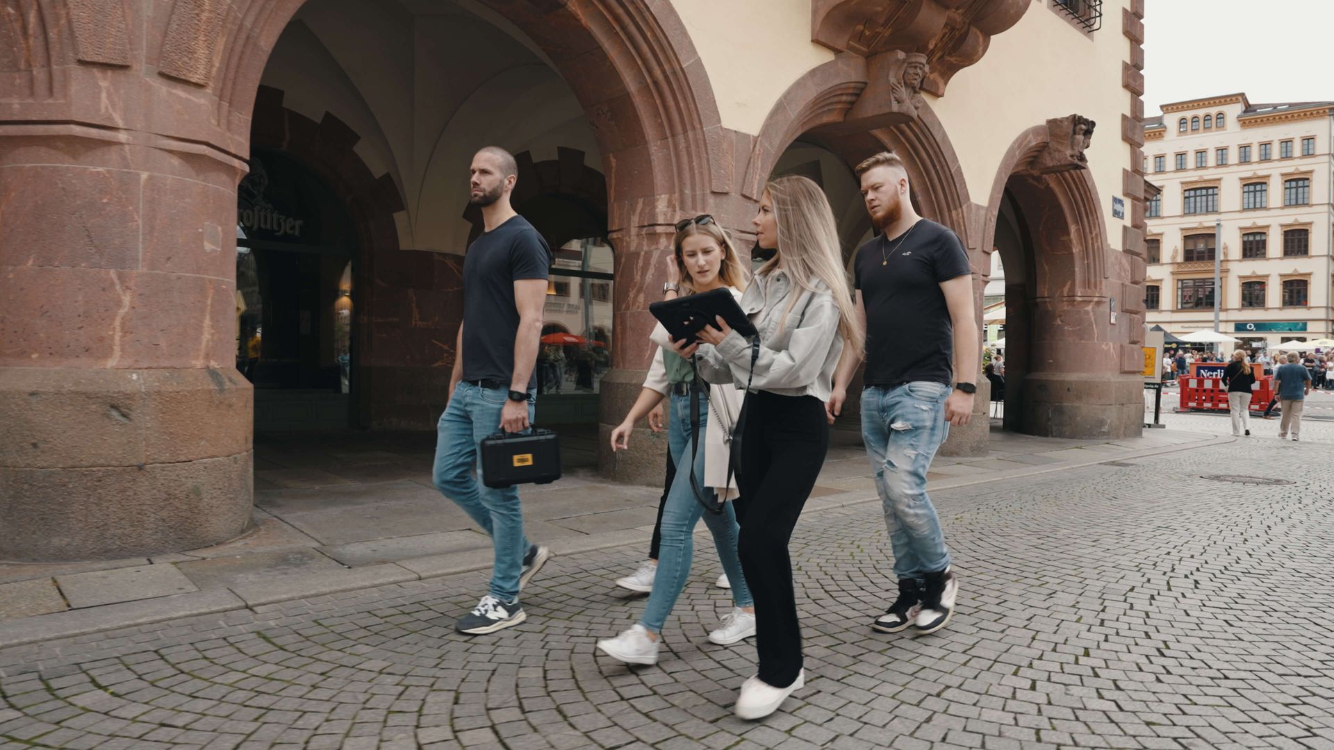 Eine Gruppe von Menschen geht eine Kopfsteinpflasterstraße entlang.