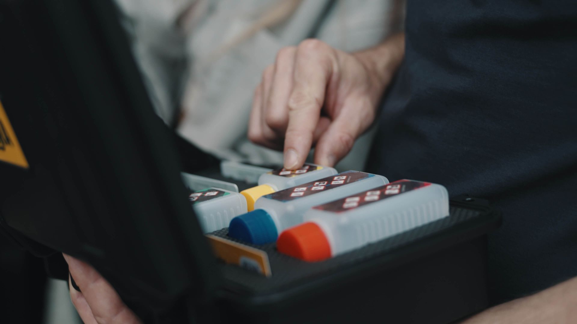 Eine Person hält eine Kiste mit Flaschen voller Flüssigkeit darin.