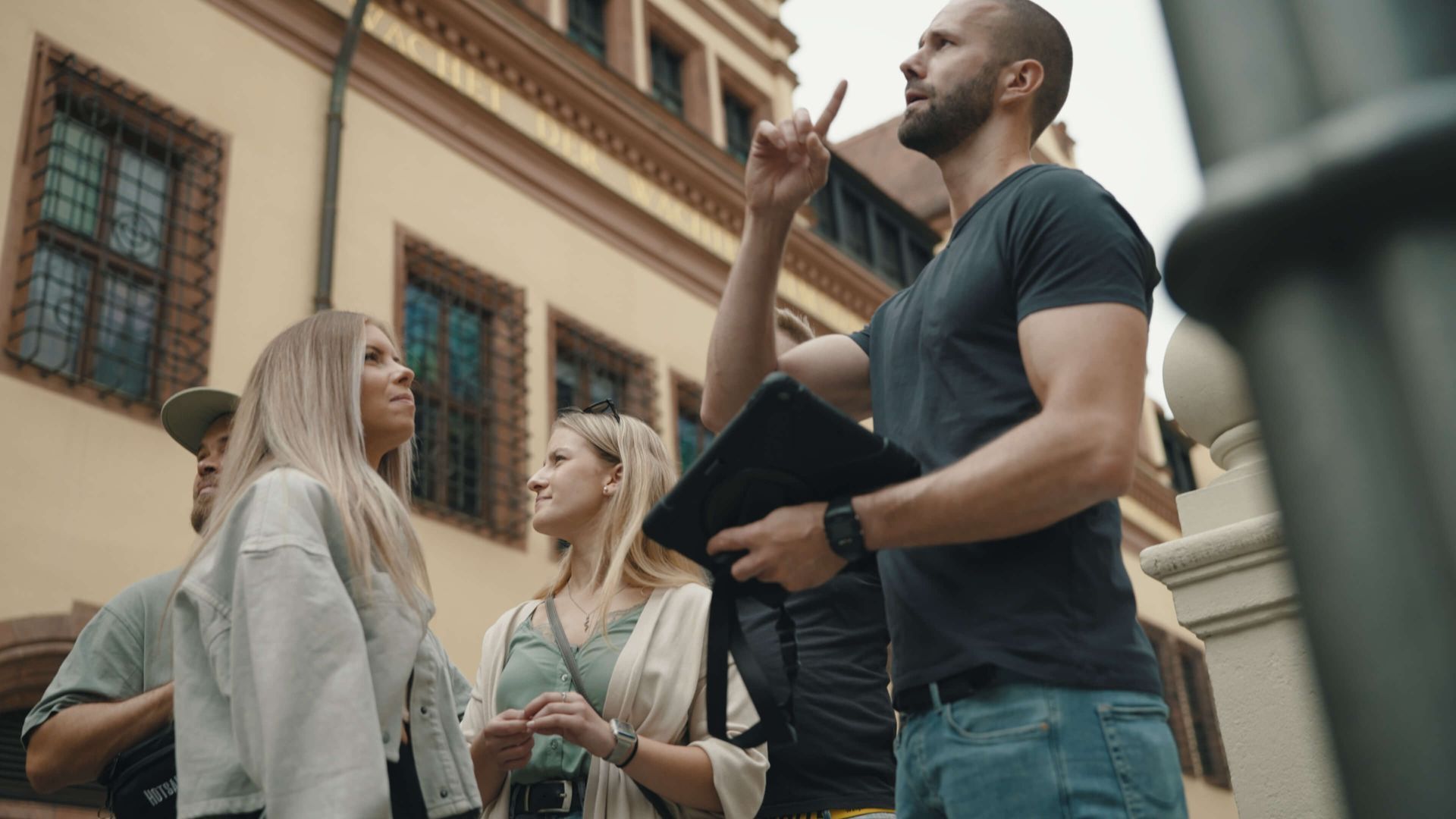 Eine Gruppe von Menschen steht vor einem Gebäude und unterhält sich miteinander.