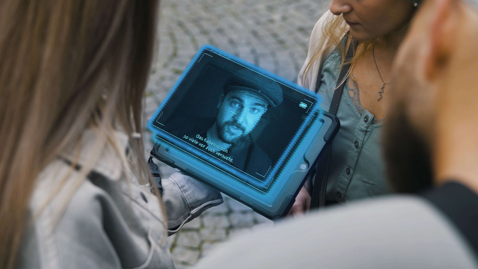Eine Frau hält ein Tablet mit dem Bild eines Mannes darauf.