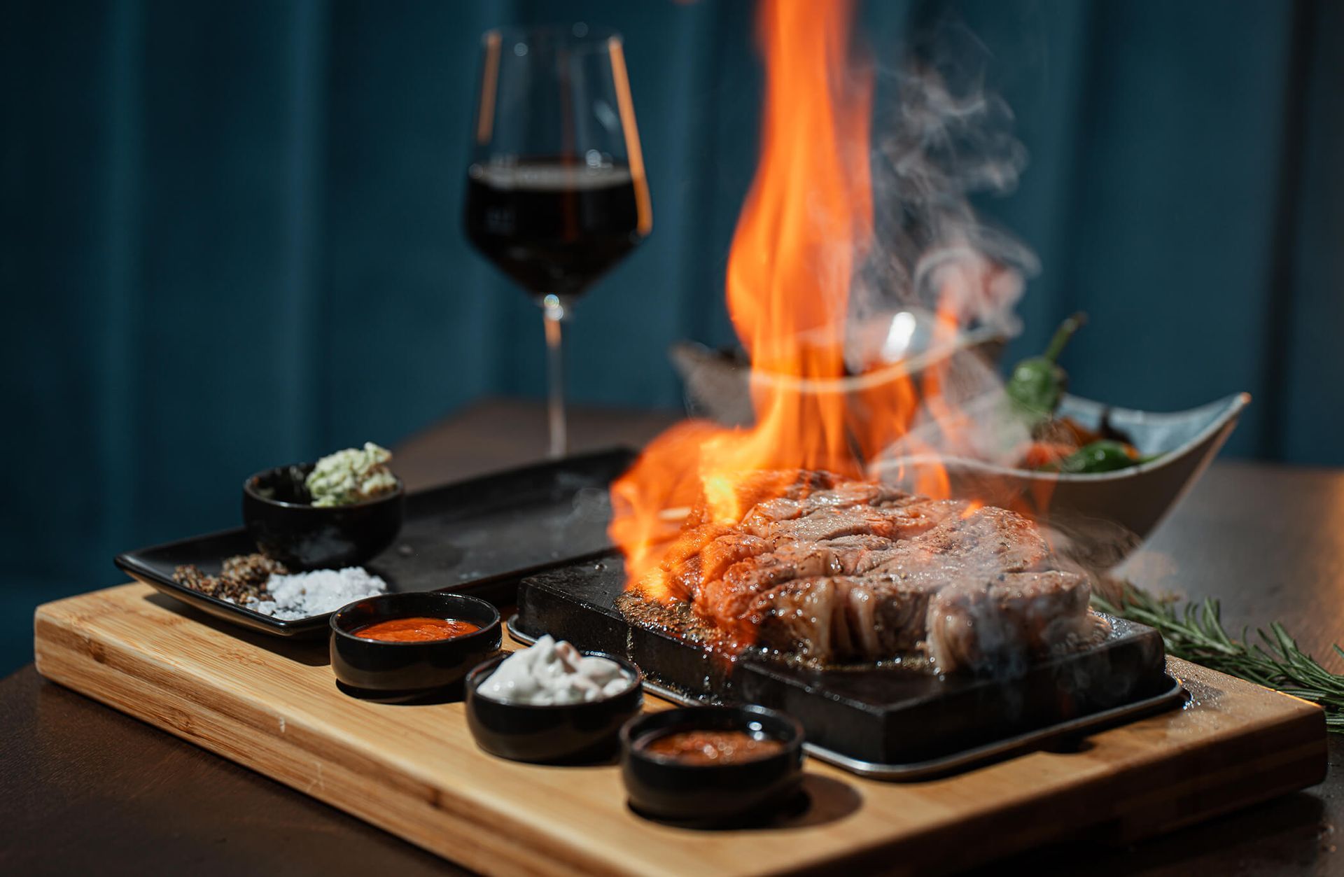 Auf einem Schneidebrett wird ein Steak bei einem Glas Wein zubereitet.