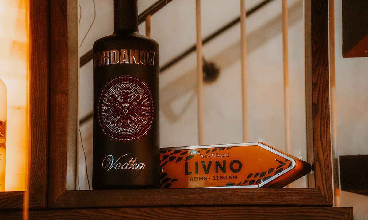 Eine Flasche Wodka steht auf einem Holzregal neben einem Schild.