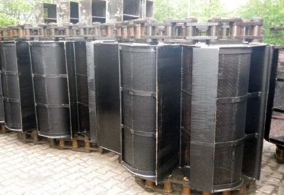 Eine Reihe schwarzer Fässer steht auf einem Ziegelsteinpflaster.