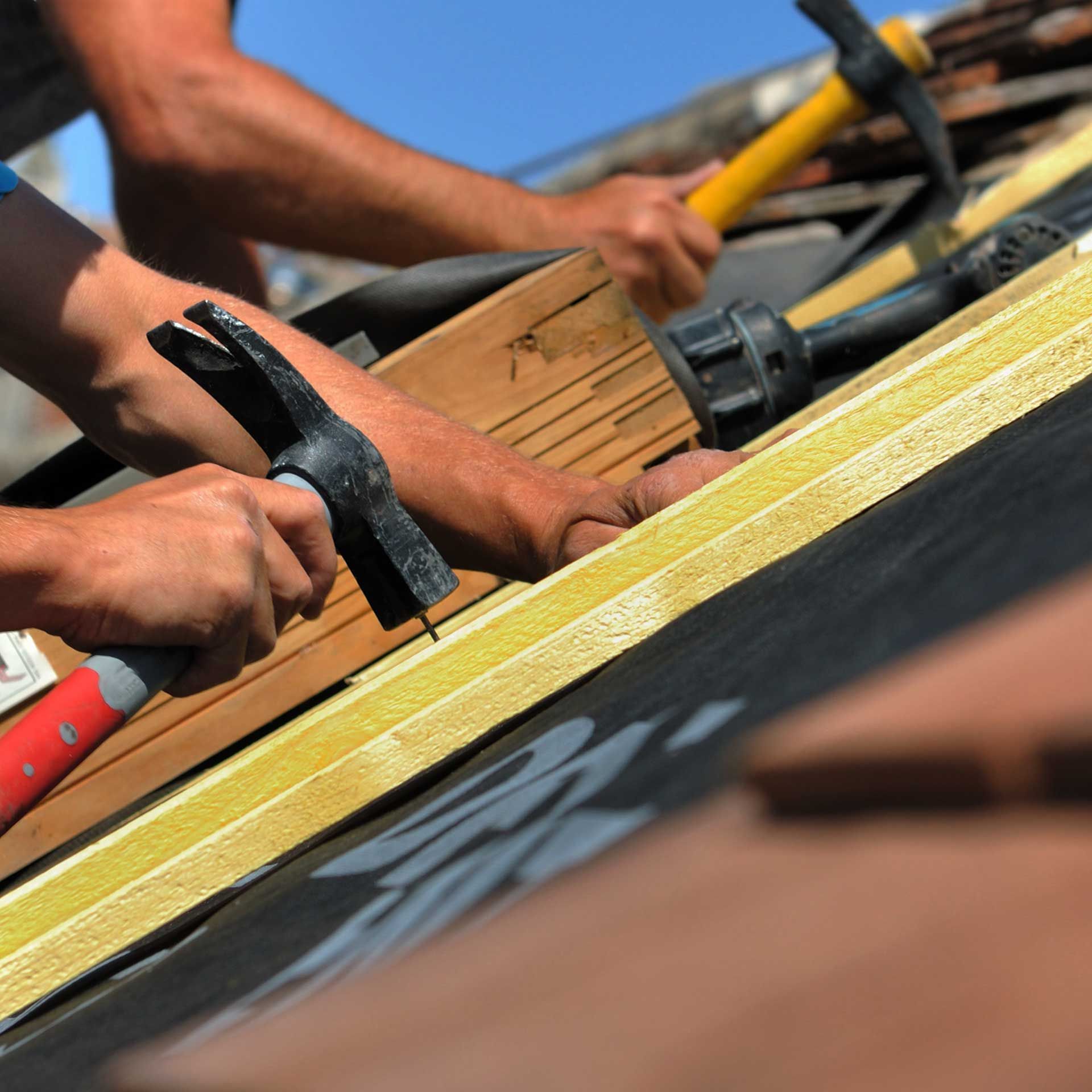 Les mains de deux charpentiers utilisant des marteaux sur un toit