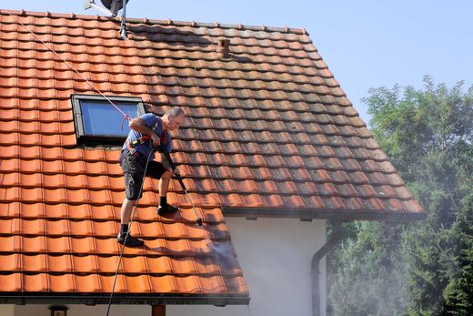 Un expert en couverture pendant le démoussage d'une toiture