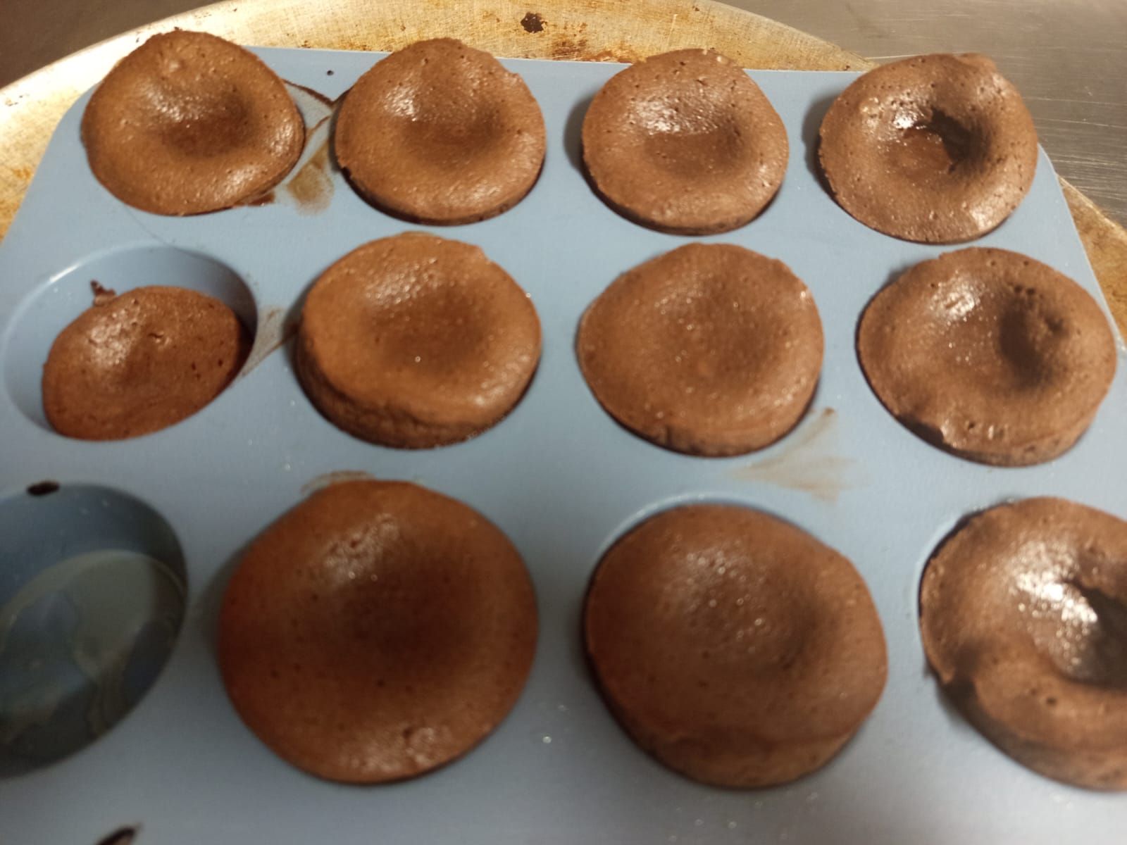 Un molde para muffins lleno de donas de chocolate sobre una mesa