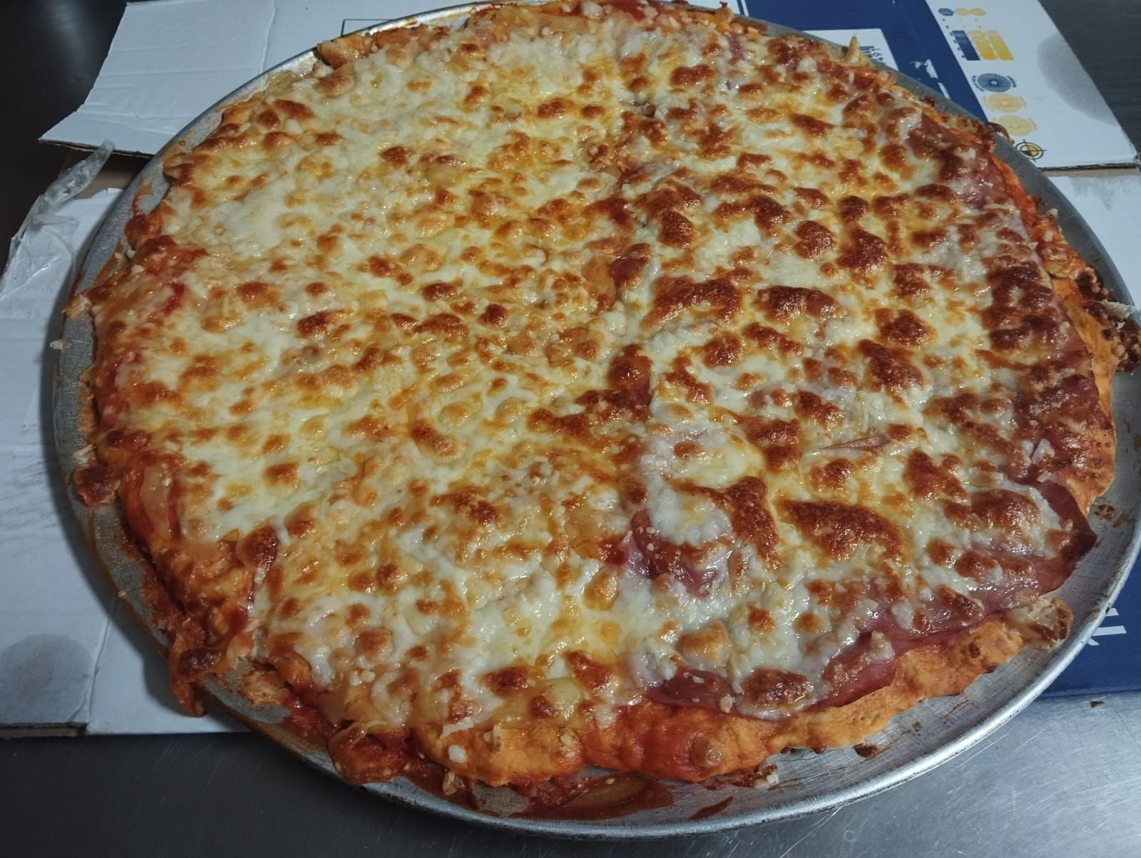 Una pizza está colocada en una sartén sobre una mesa.