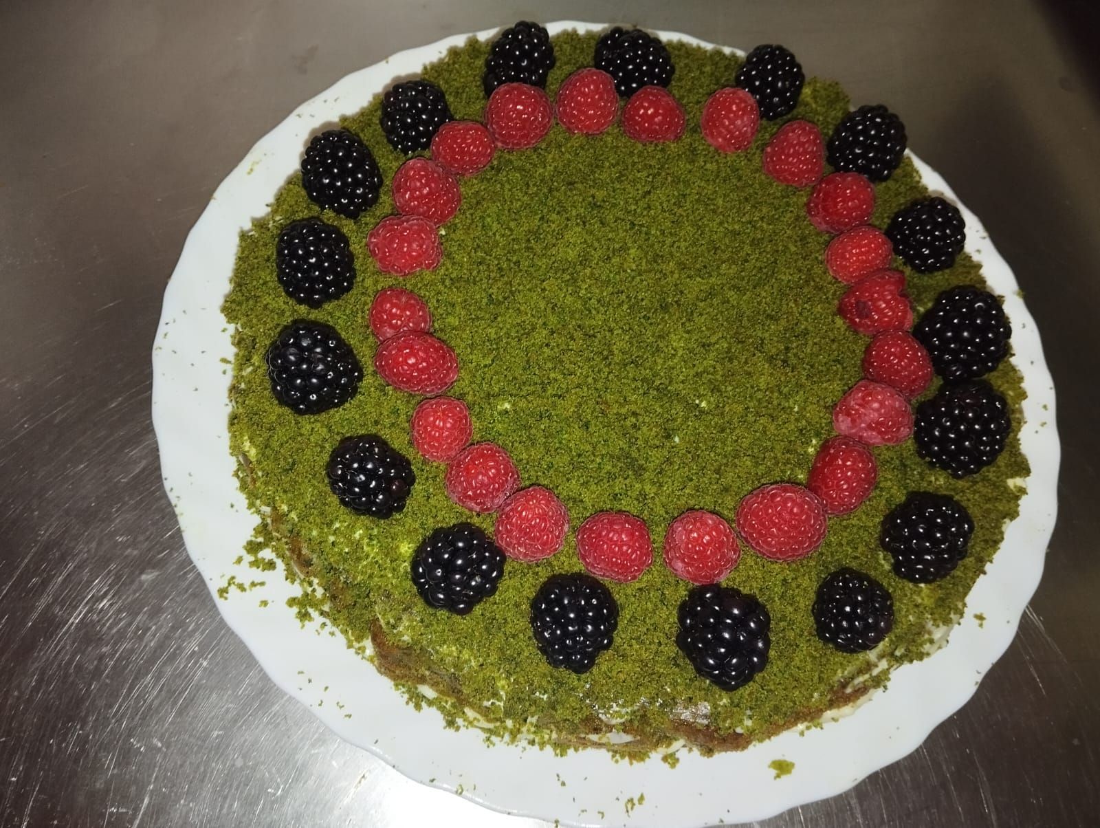 Un pastel con moras y frambuesas encima.