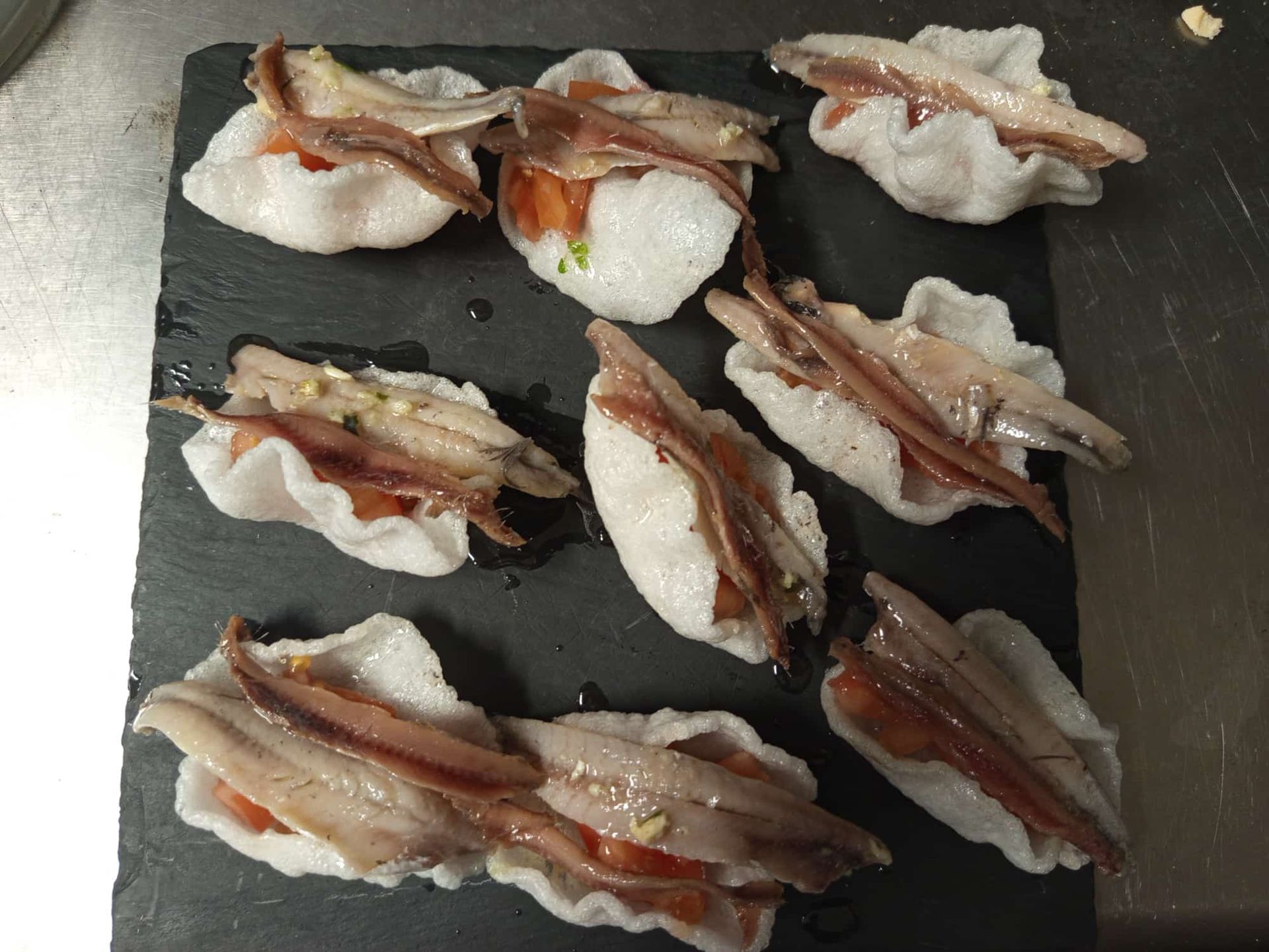 Un plato de comida con anchoas y tomates encima.