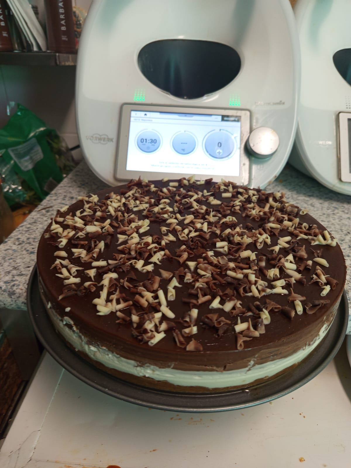 Un pastel está sobre un plato en un mostrador al lado de una licuadora.