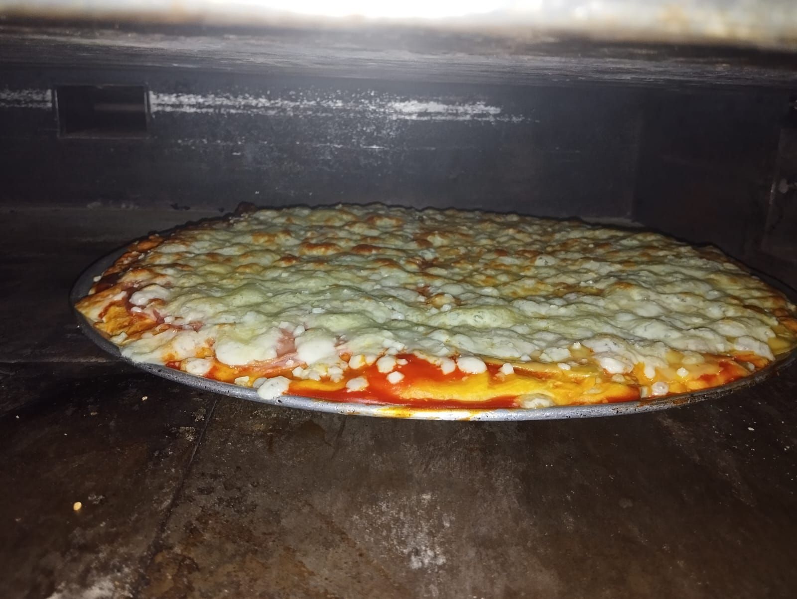 Una pizza está colocada sobre una sartén dentro de un horno.
