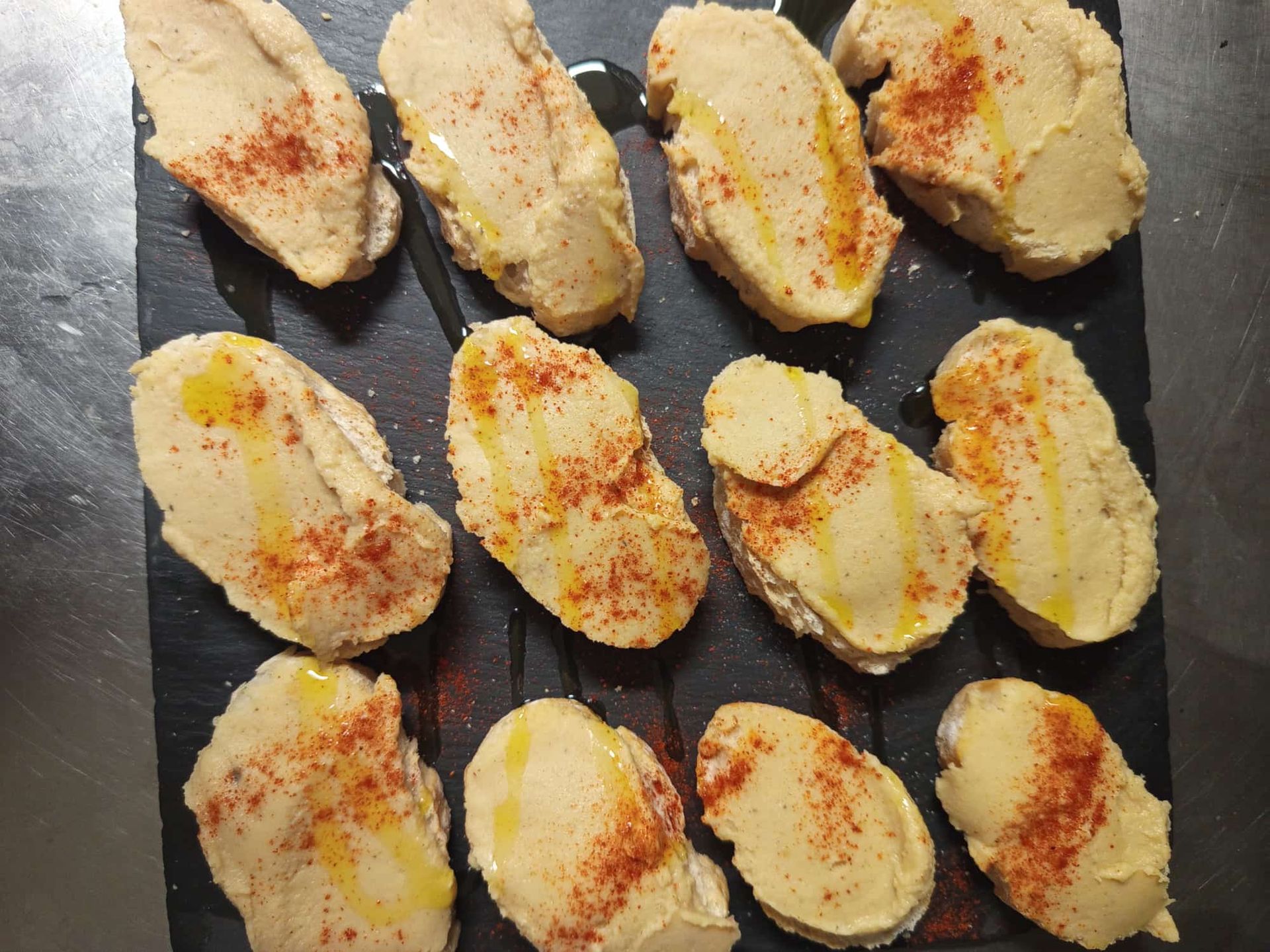 Un plato negro cubierto con rebanadas de pan cubiertas de aceite y pimentón.