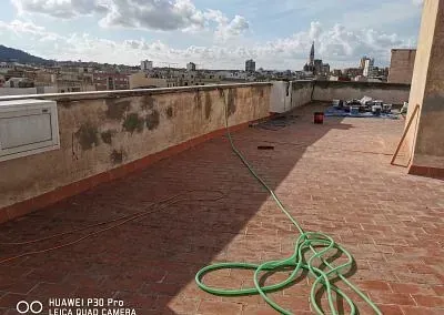 Una manguera verde está tendida sobre un tejado de tejas.