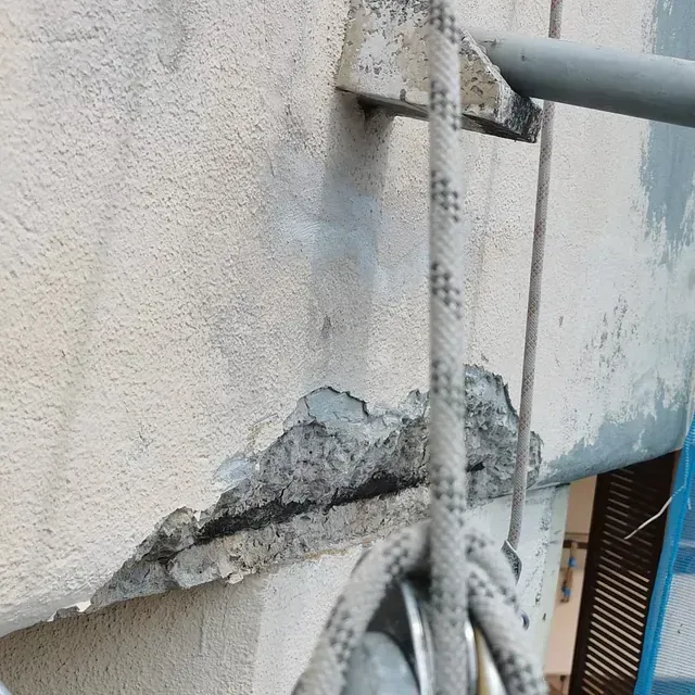 Una cuerda cuelga de un poste de metal en una pared.