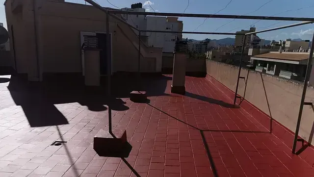 Un techo de tejas rojas con una barandilla de metal sobre él.