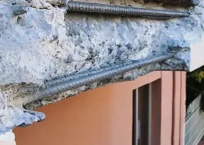 Un primer plano de una pared de hormigón con una ventana al fondo.