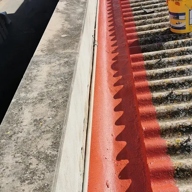 Un cubo amarillo se encuentra en un techo junto a una canaleta roja.