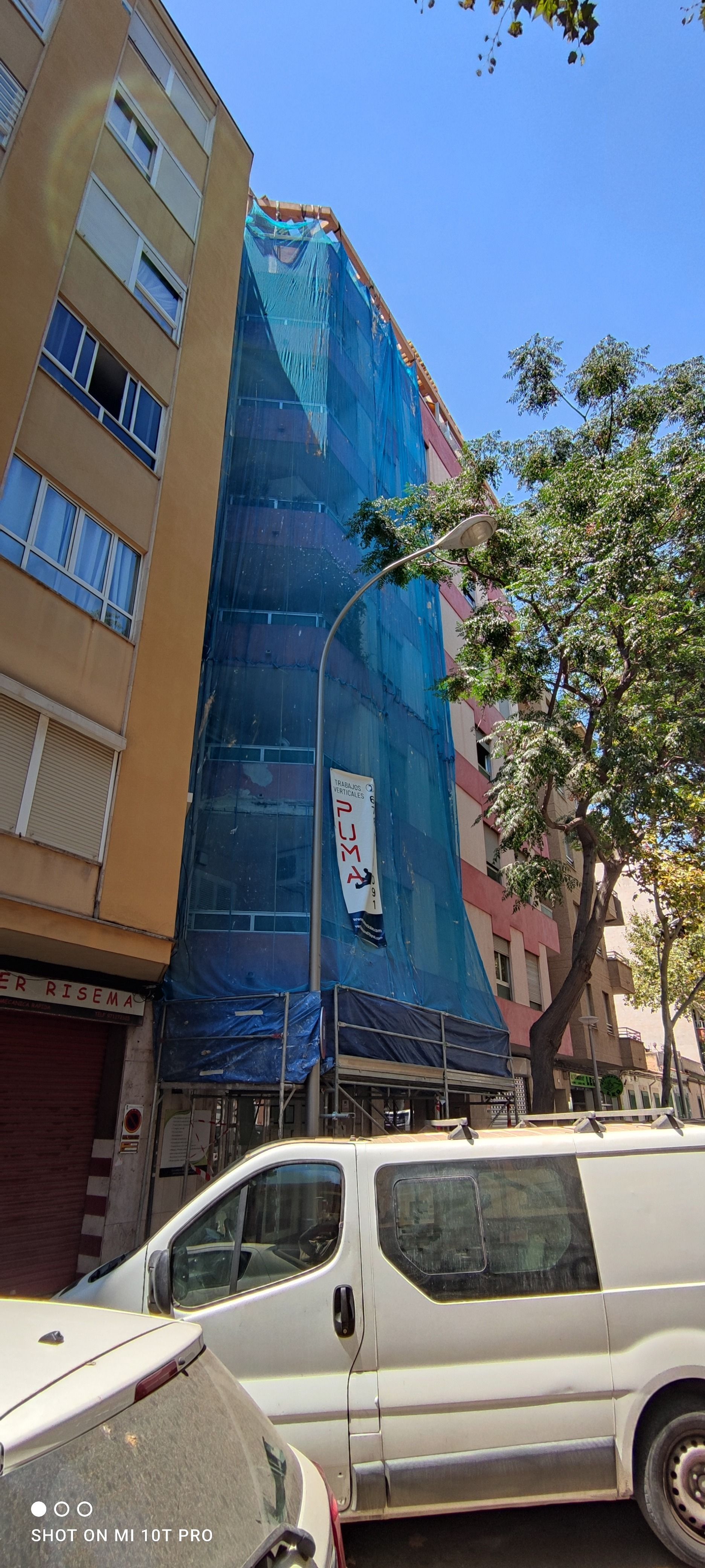 Una furgoneta blanca está estacionada delante de un edificio en construcción.