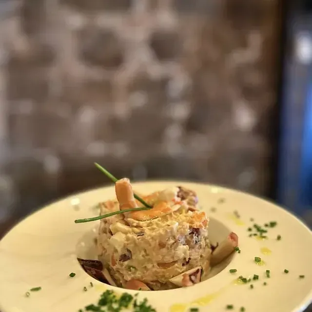 Un primer plano de un plato de comida con un camarón encima.