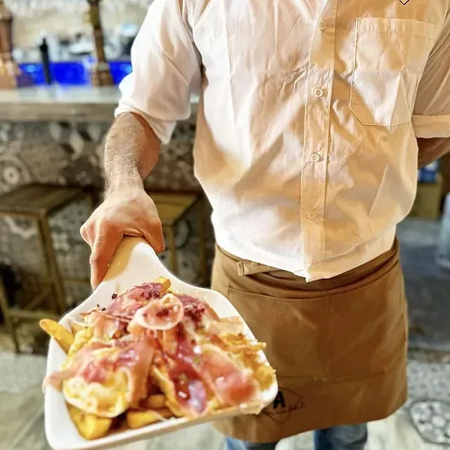Un hombre con delantal sostiene un plato de comida.