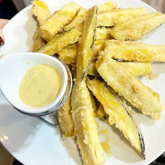 Un plato de comida con un tazón pequeño de salsa para mojar