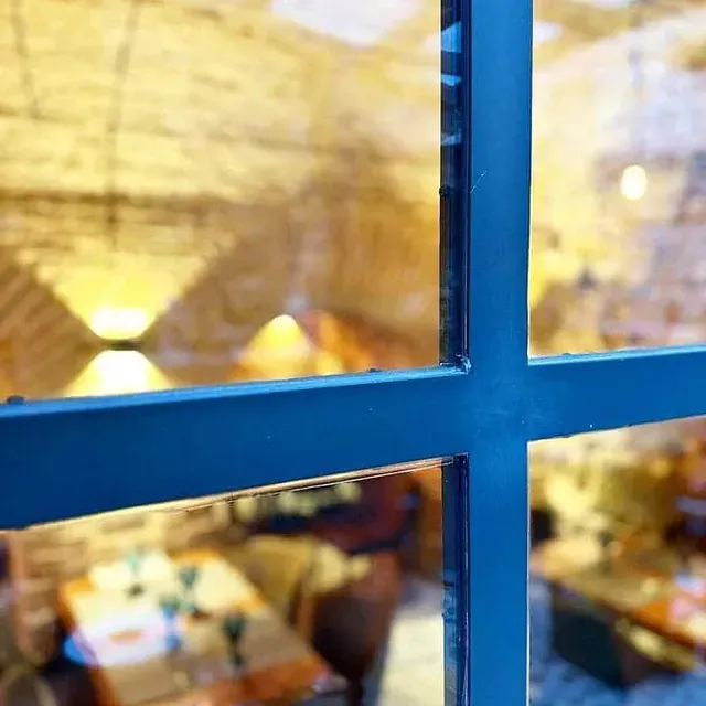 Una ventana azul con el reflejo de un restaurante en ella.