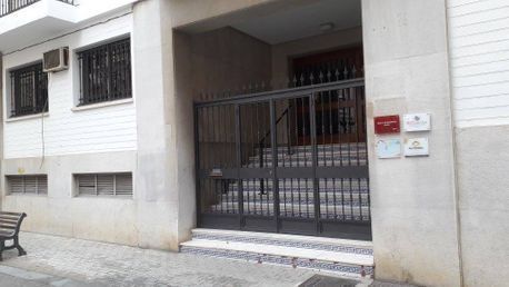 Un edificio con una valla y un banco delante.