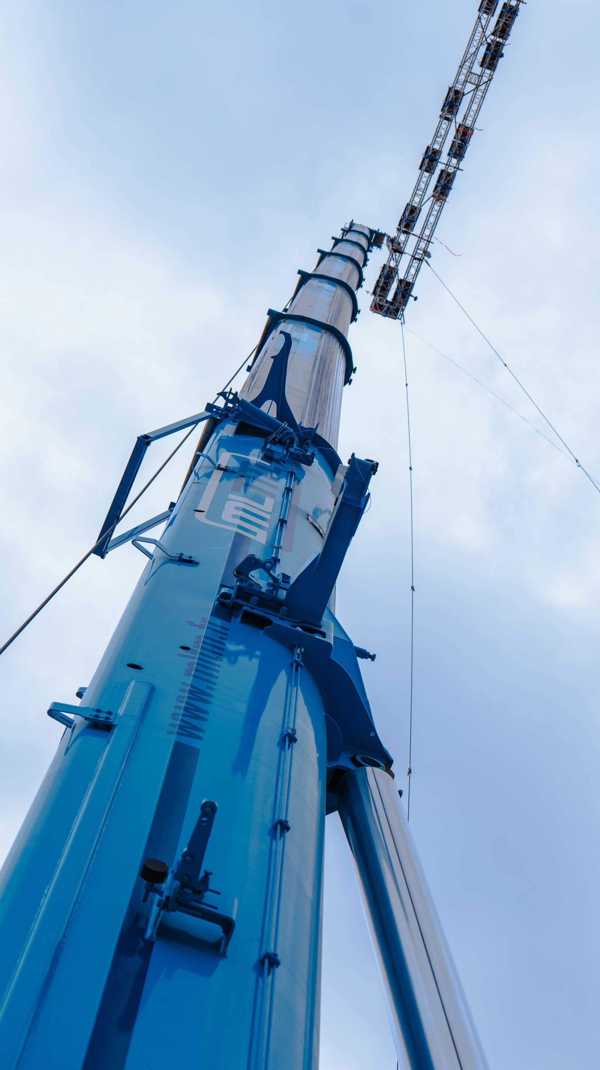 Détail d'un bras de grue mobile et logo de l'entreprise MLTM