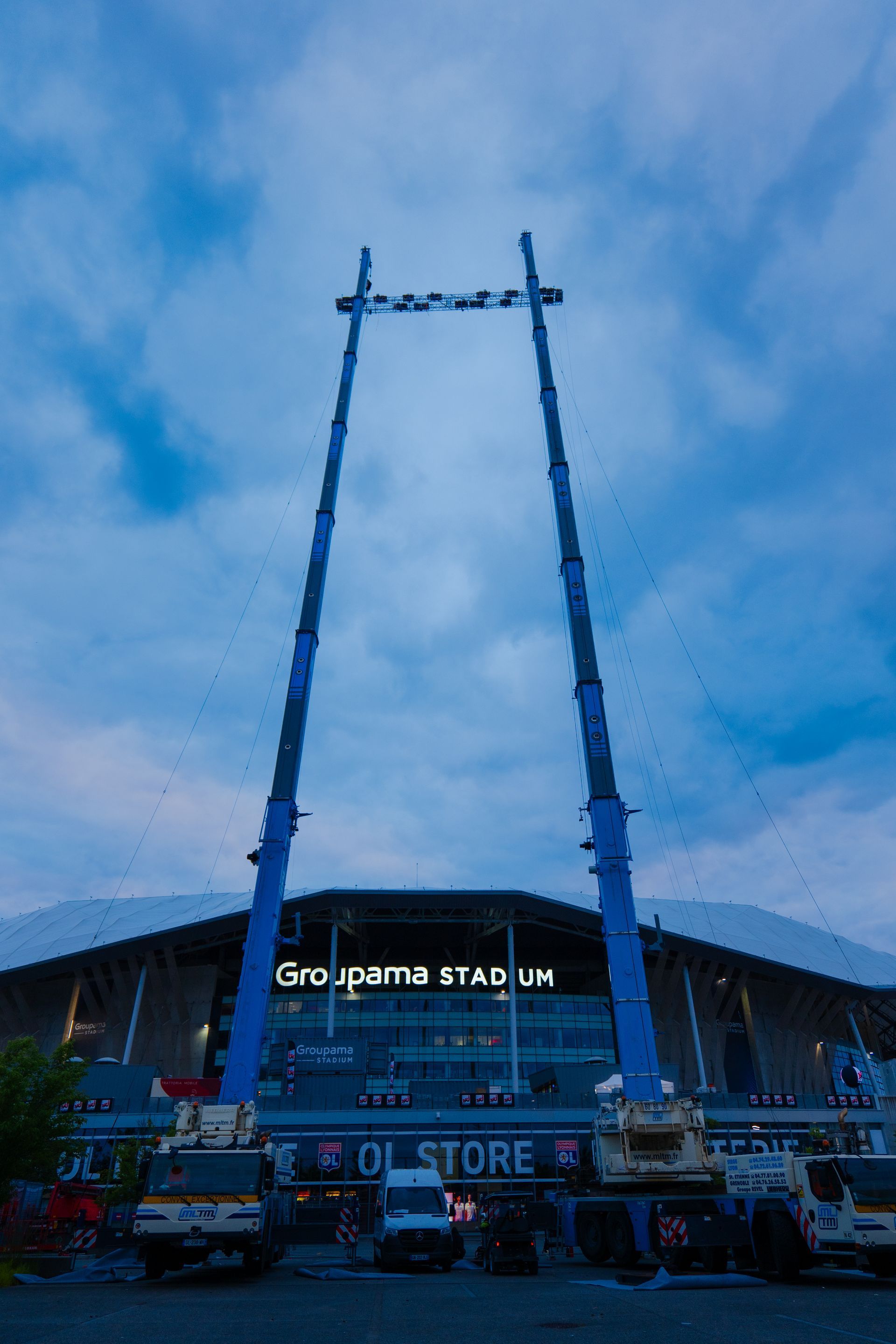 Deux grues mobiles avec des bras dépliés devant le Groupama Stadium