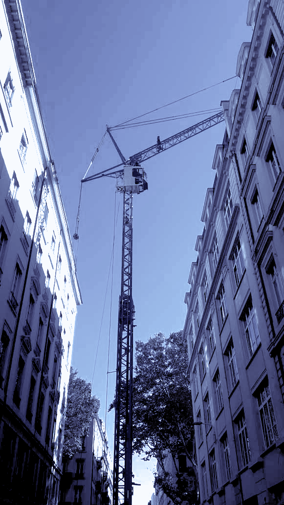 Une grue en hauteur devant un bâtiment