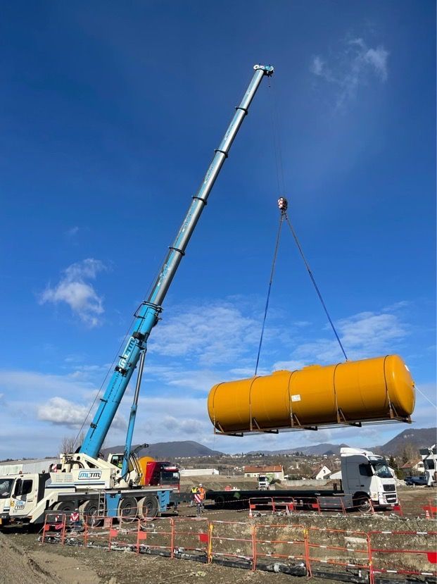 Manutention d'une citerne jaune à l'aide d'une grue mobile