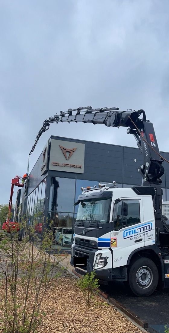 Camion avec son bras déployé devant une enseigne