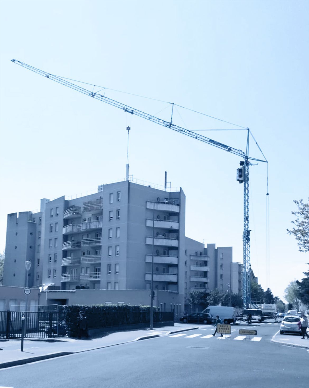 Camion grue avec nacelle devant un immeuble