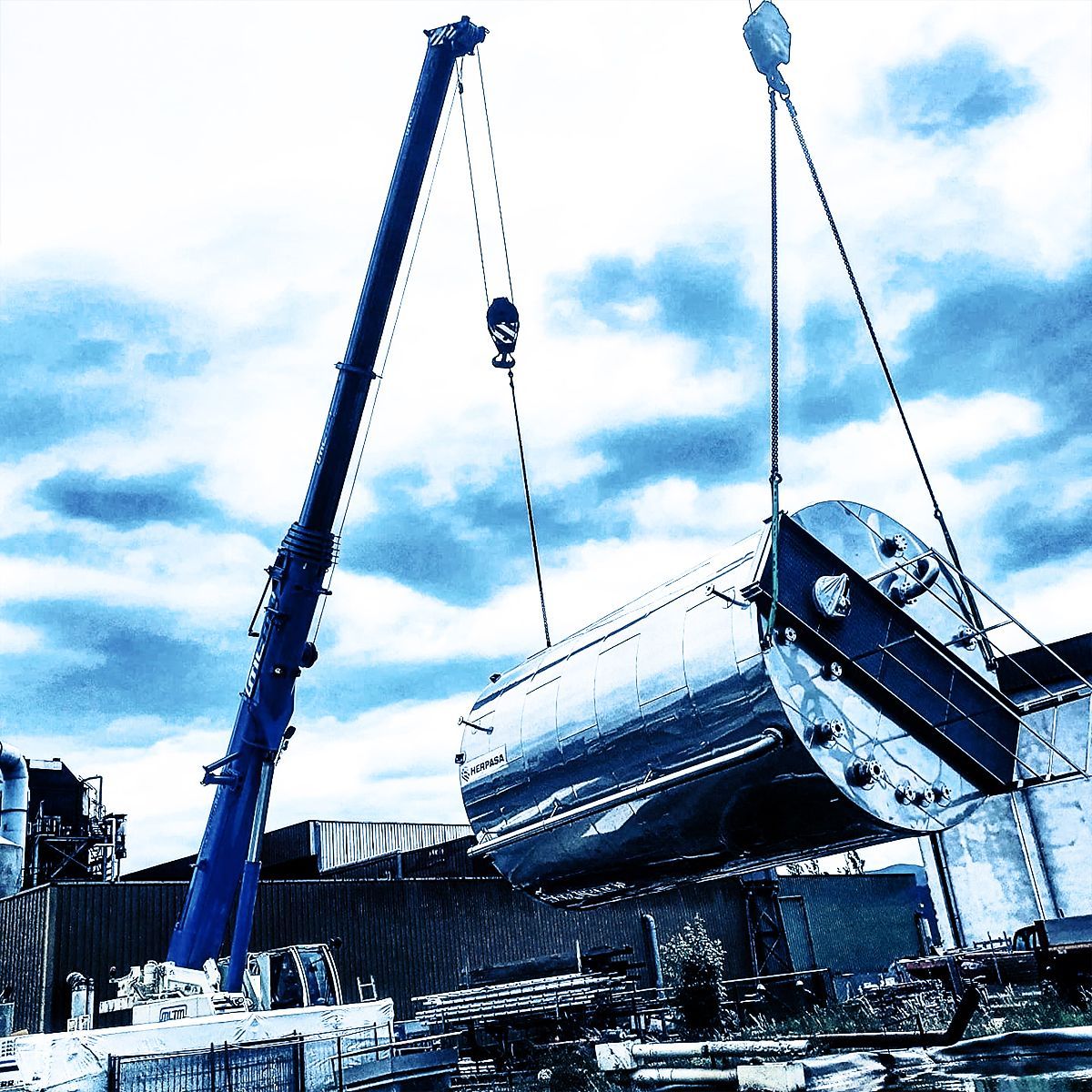Levage d'un bidon métallique sur fond de ciel nuageux