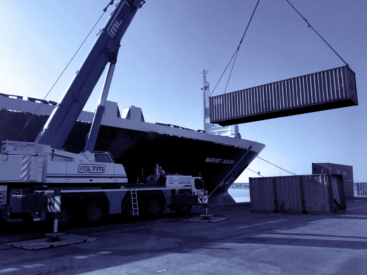 Une grue dépose un container sur un bateau