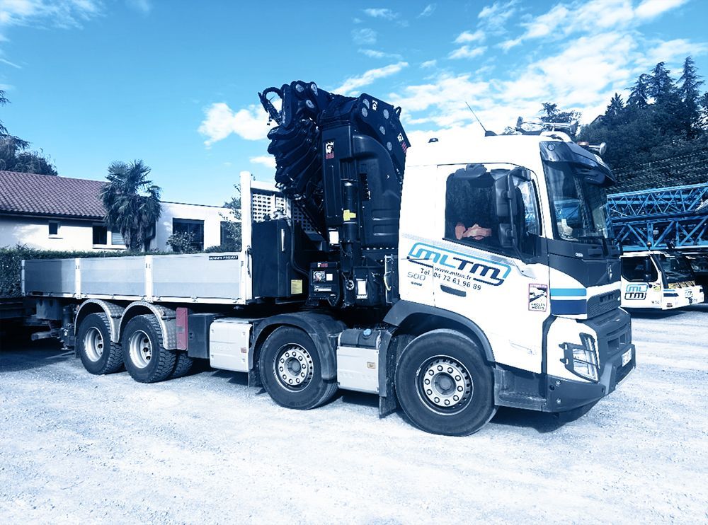 Camion avec bras de levage devant une structure métallique